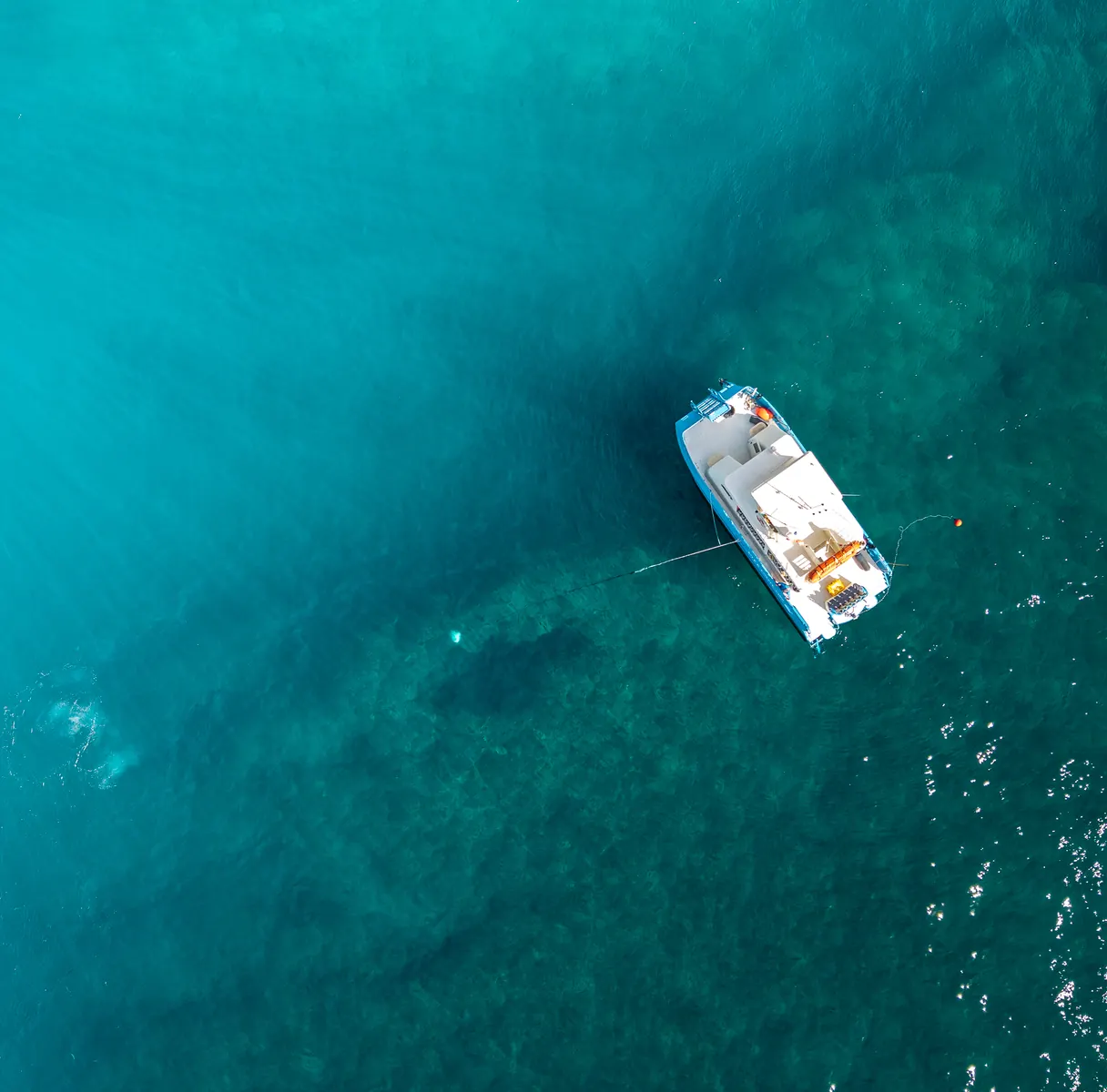 Aerial view of a dive boat anchored over turquoise water