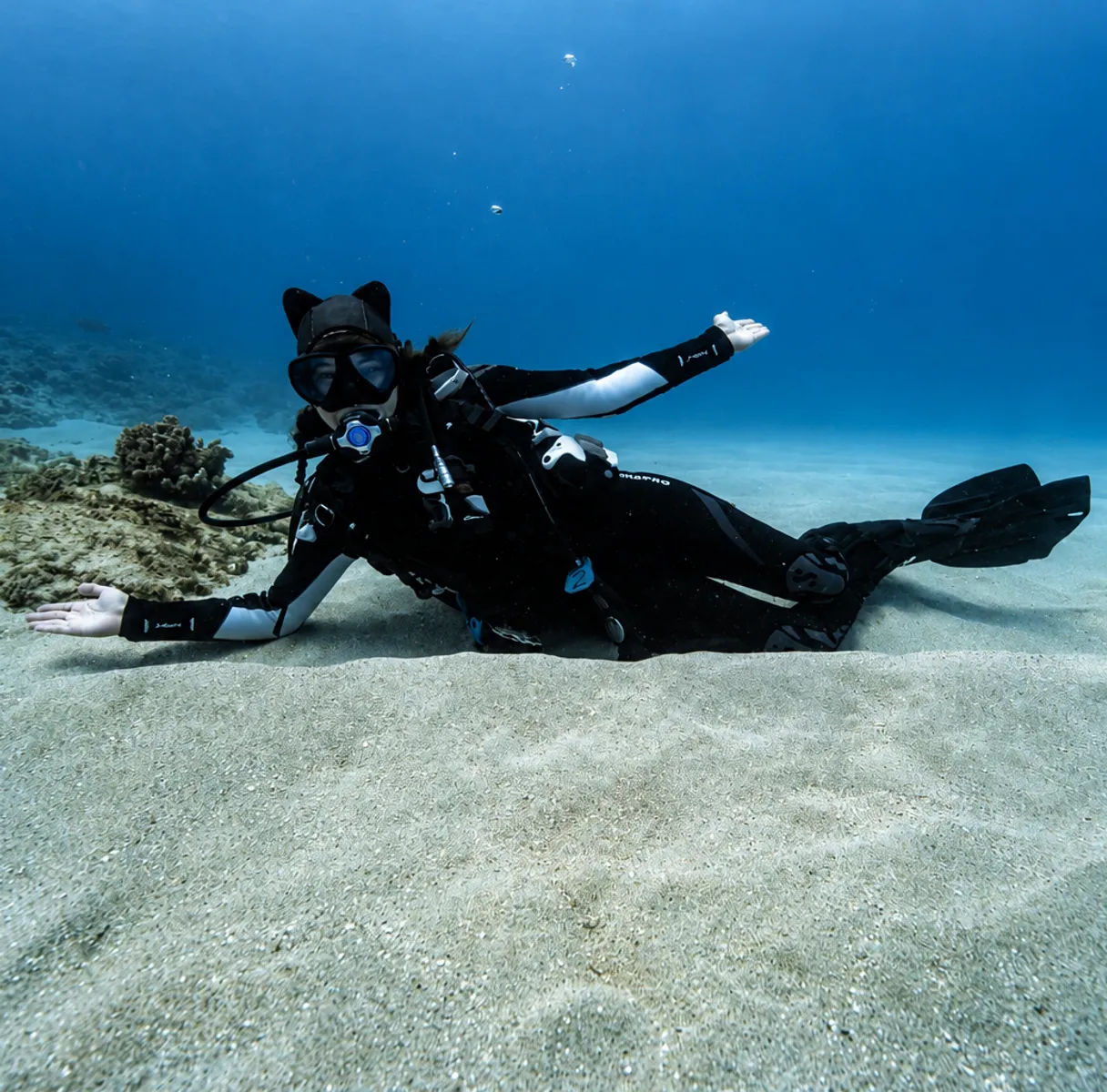 Scuba diver hovering over a sandy seabed in clear blue water