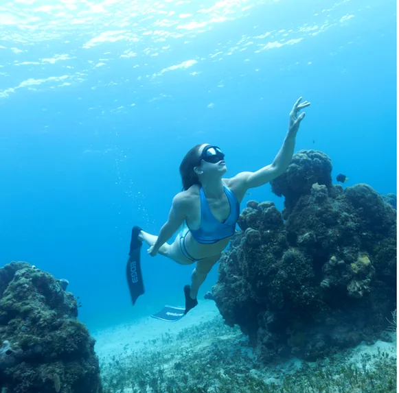 Freediver gliding over a coral reef